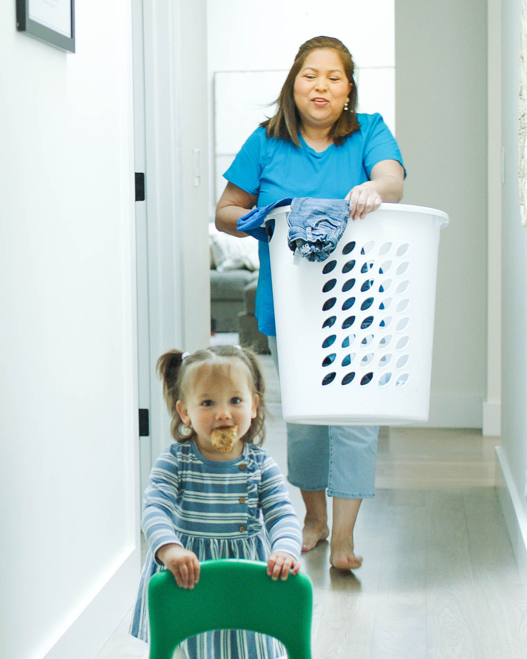 Person carrying a laundry basket and a child with food on their face
