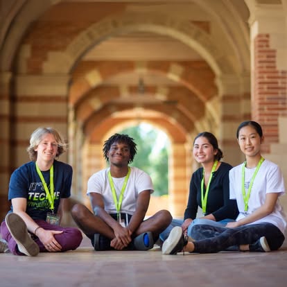Four people sitting on the ground in an arched hallway