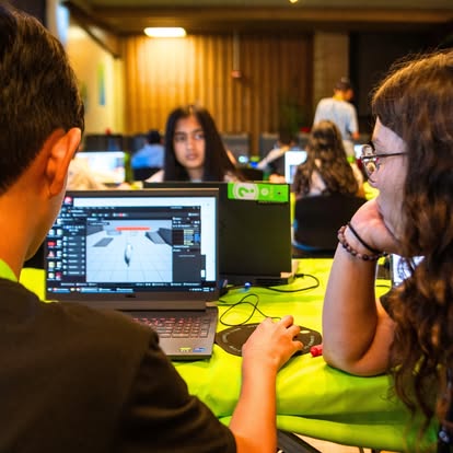 Two people working on laptops, one with a 3D design program open