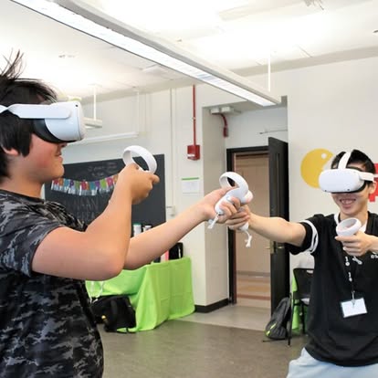 Two teens wearing VR headsets and holding controllers