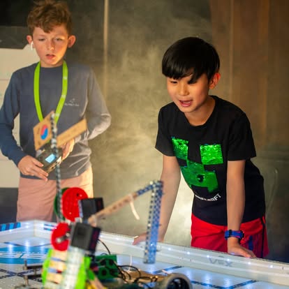 Two children interacting with a robot on a table