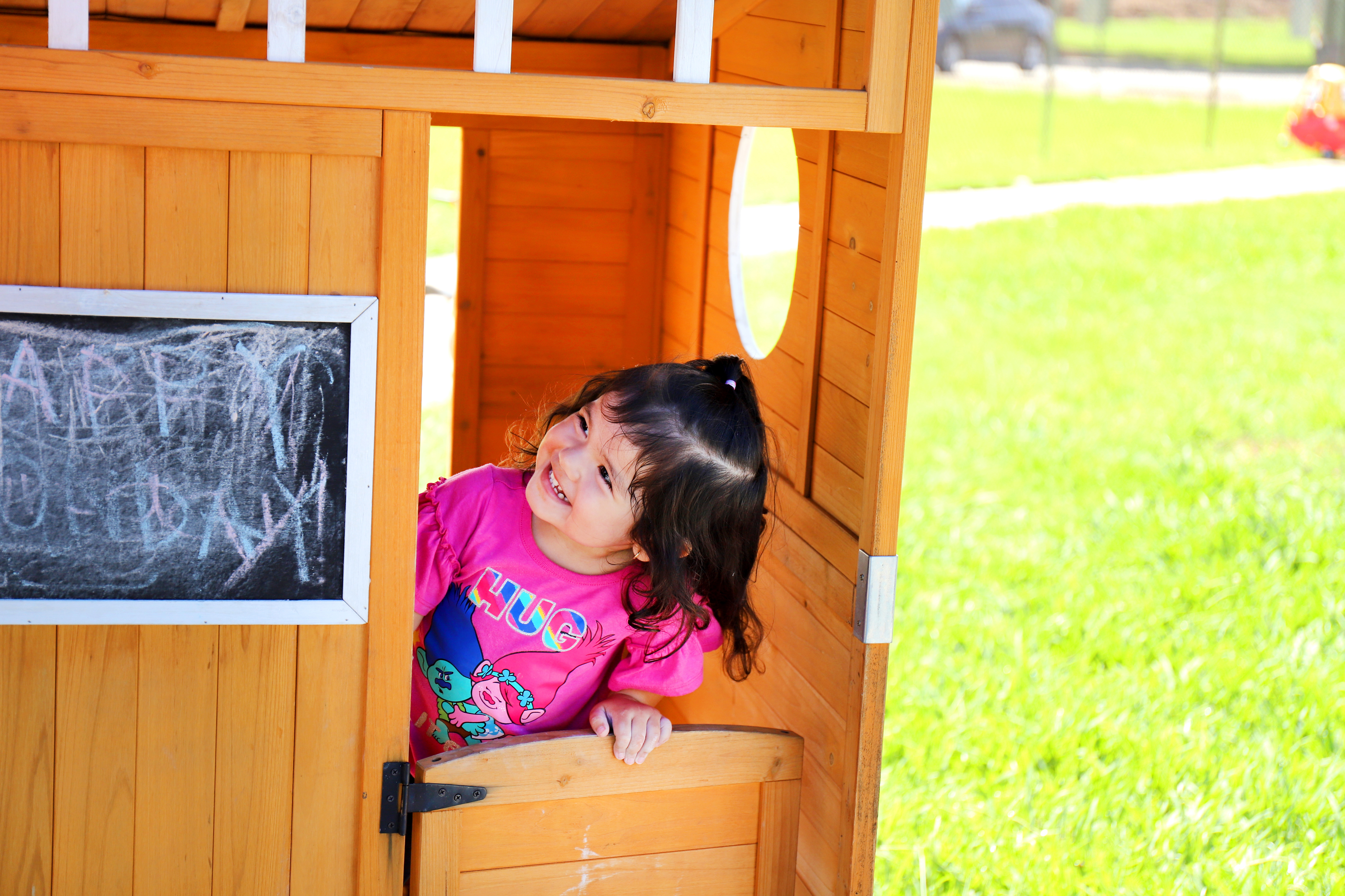 Child looking out from a wooden playhouse
