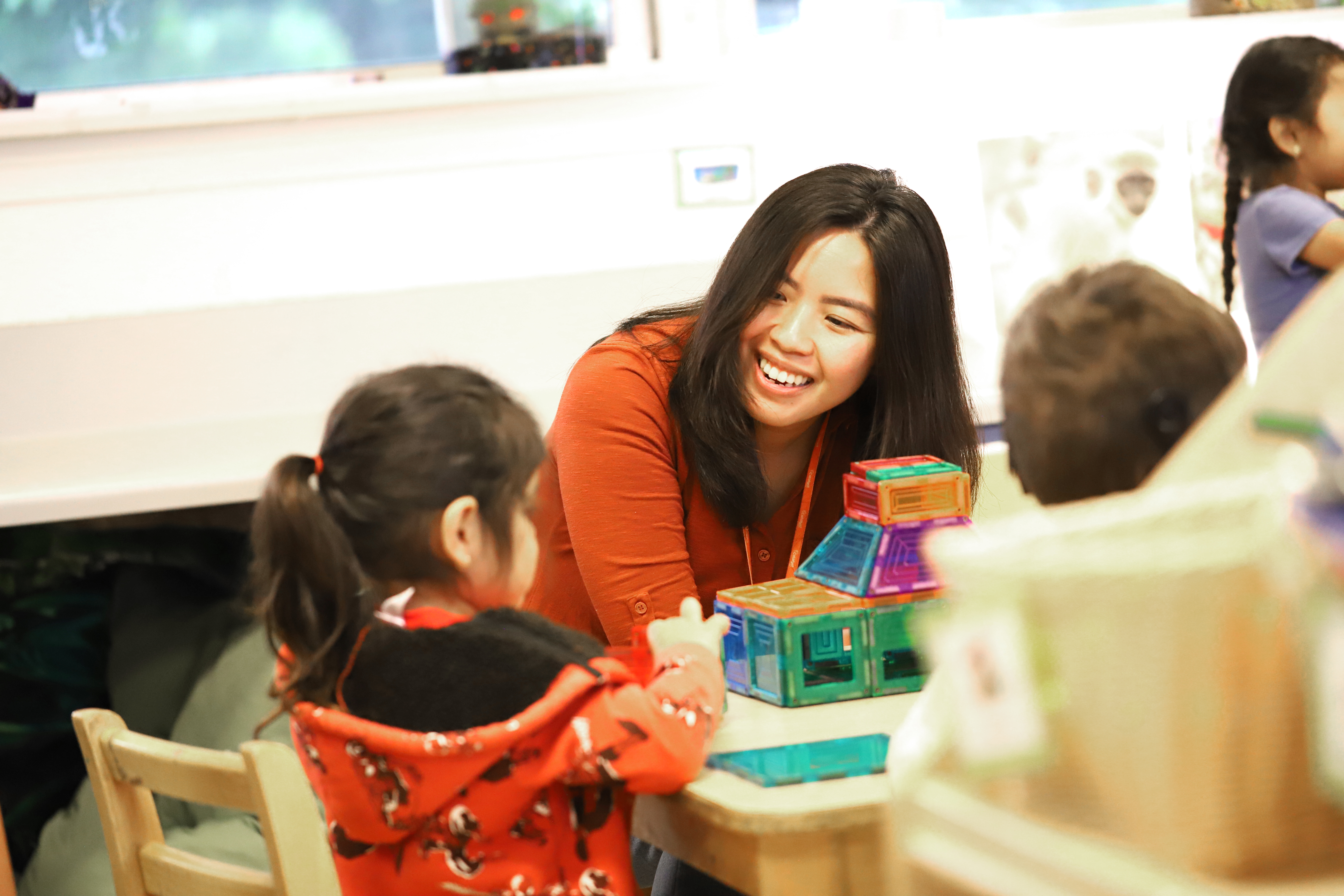 Person interacting with a child at a table with building blocks