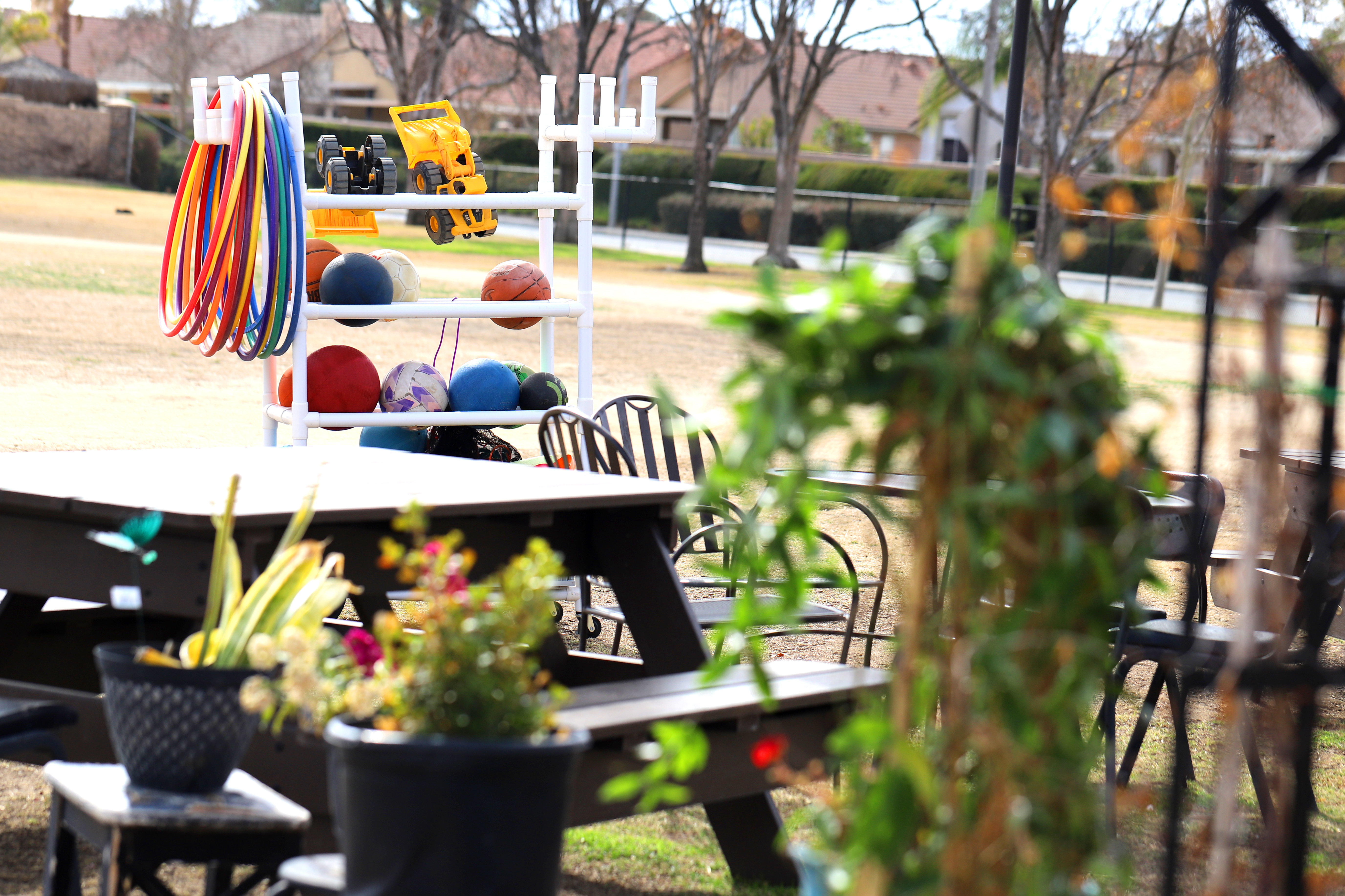 Outdoor picnic table with a rack of sports equipment and hula hoops