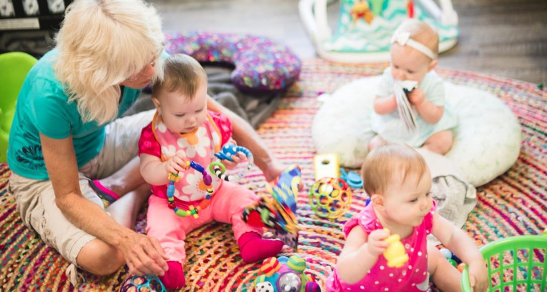 Person with three children playing on a rug