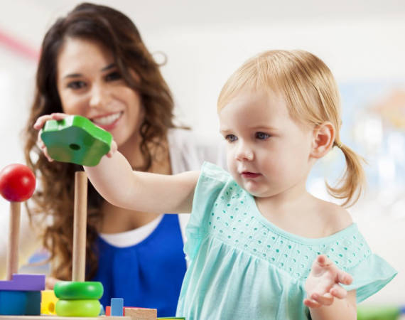 Person and child playing with a wooden stacking toy