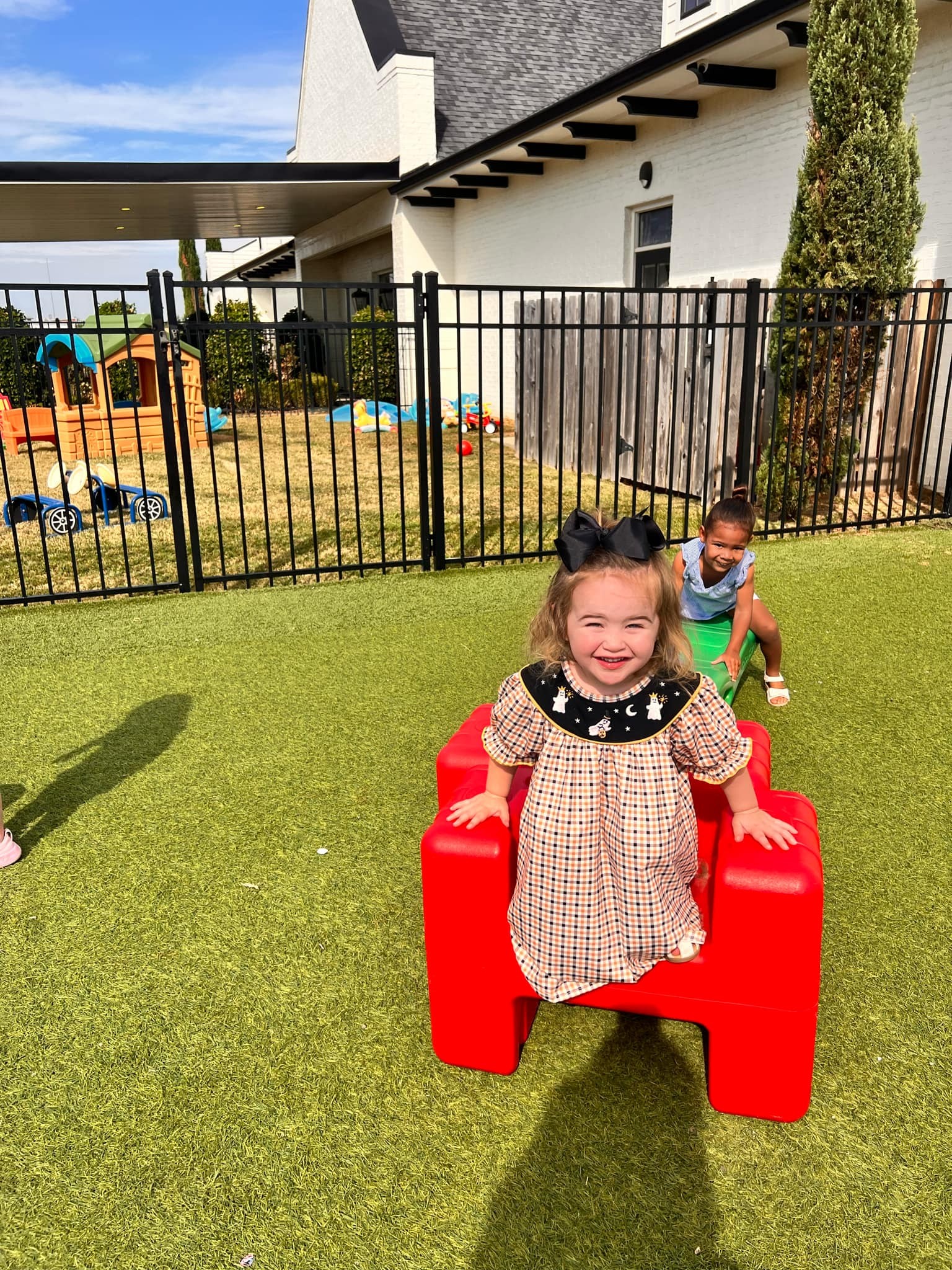 Two children playing on a green outdoor playground