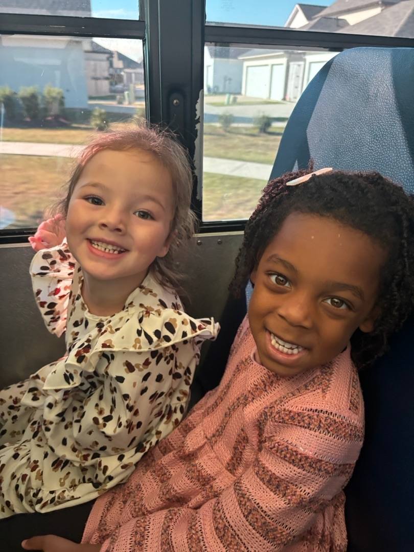 Two smiling children sitting on a bus