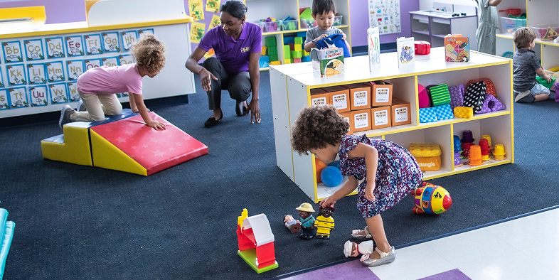Teacher and three children playing in a classroom