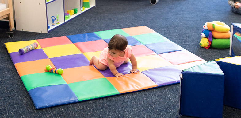 Child crawling on a colorful play mat