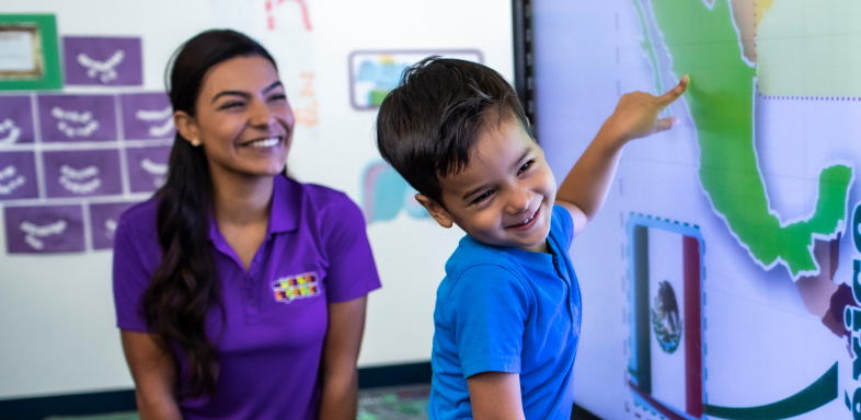 Adult and child in a classroom pointing at a map of Mexico