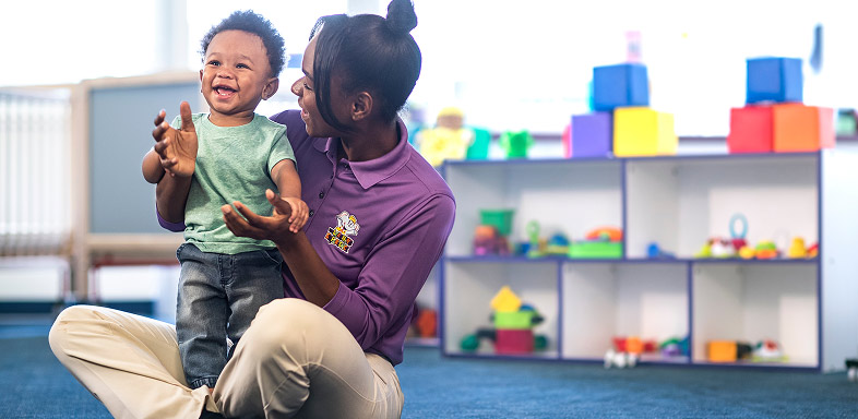 Adult and child interacting in a classroom with toys