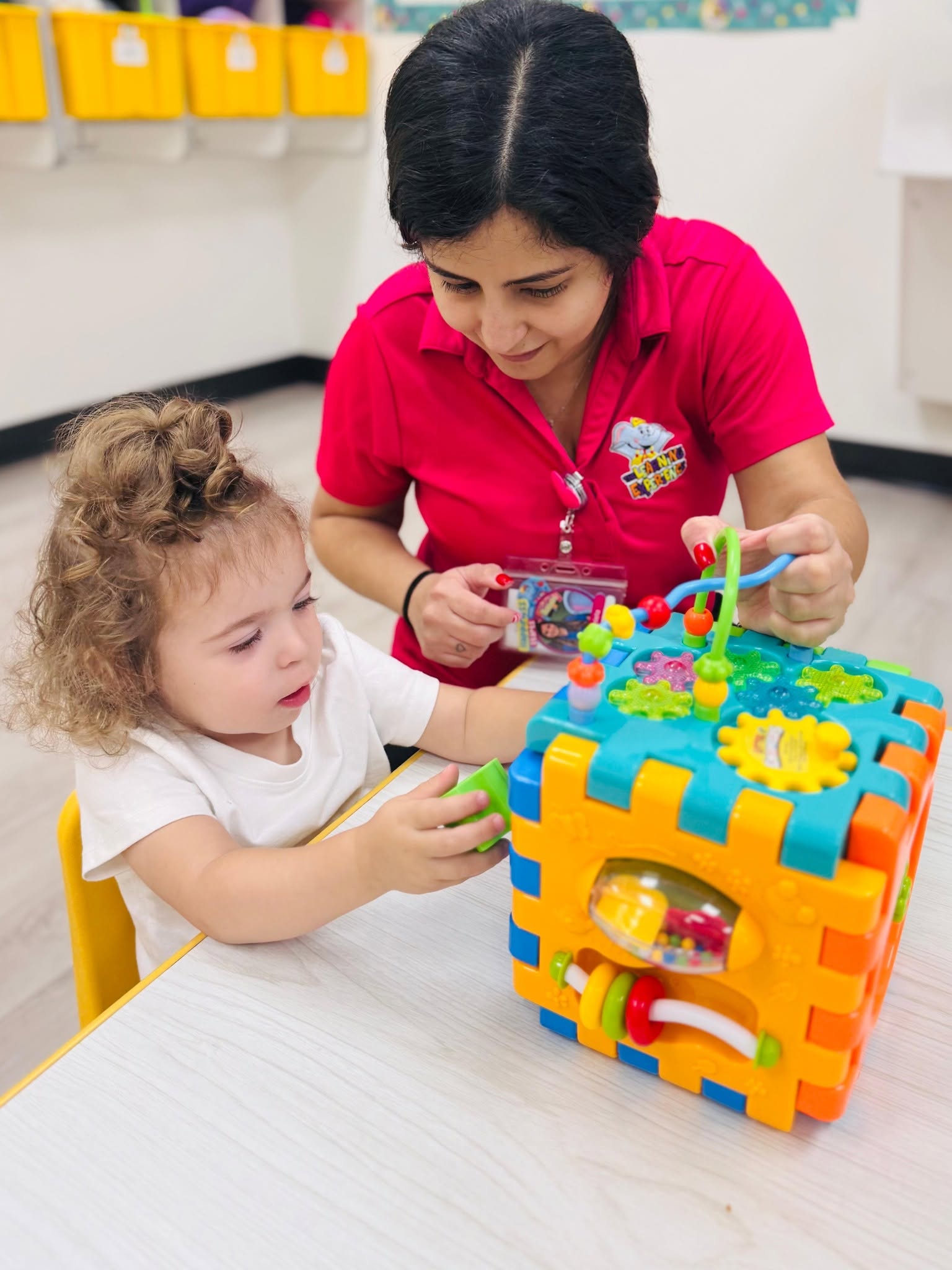 Adult and child playing with an activity cube at a table