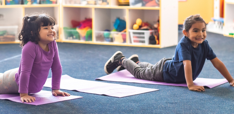 Two children doing yoga on mats in a classroom