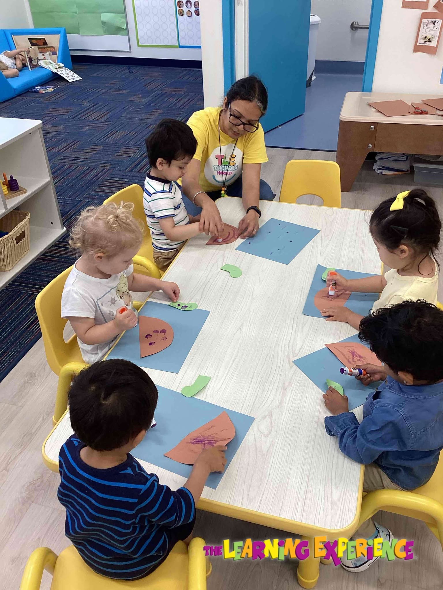 Adult with four children doing an art activity at a table