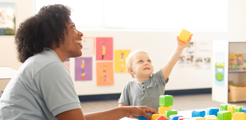 Adult and child playing with colorful blocks in a classroom