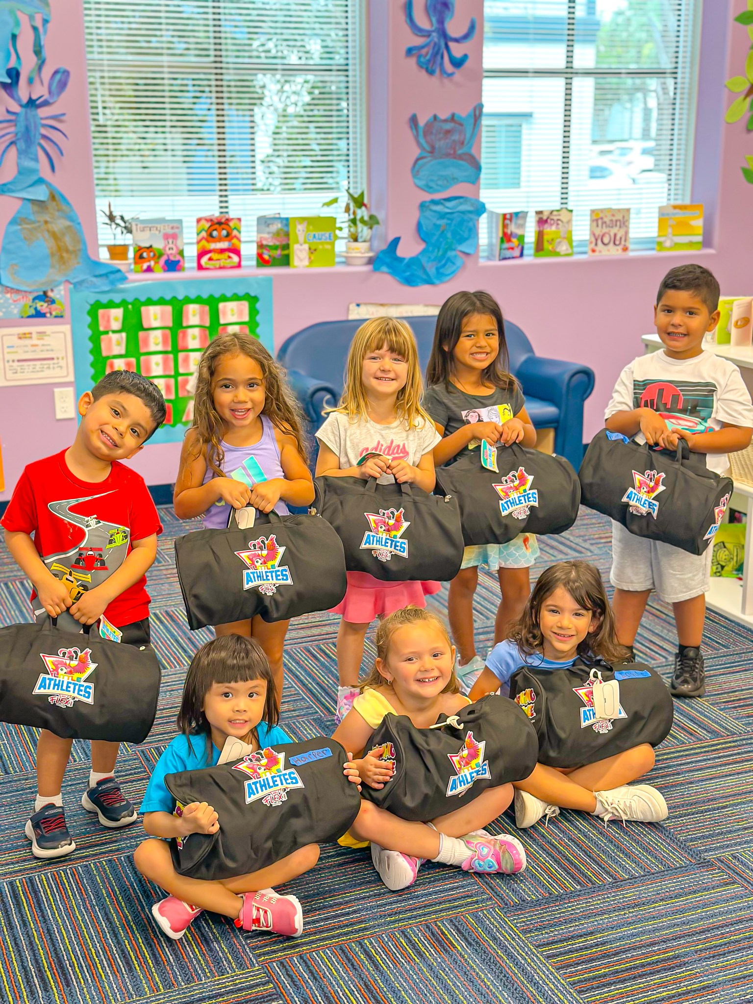 Group of children holding black duffel bags