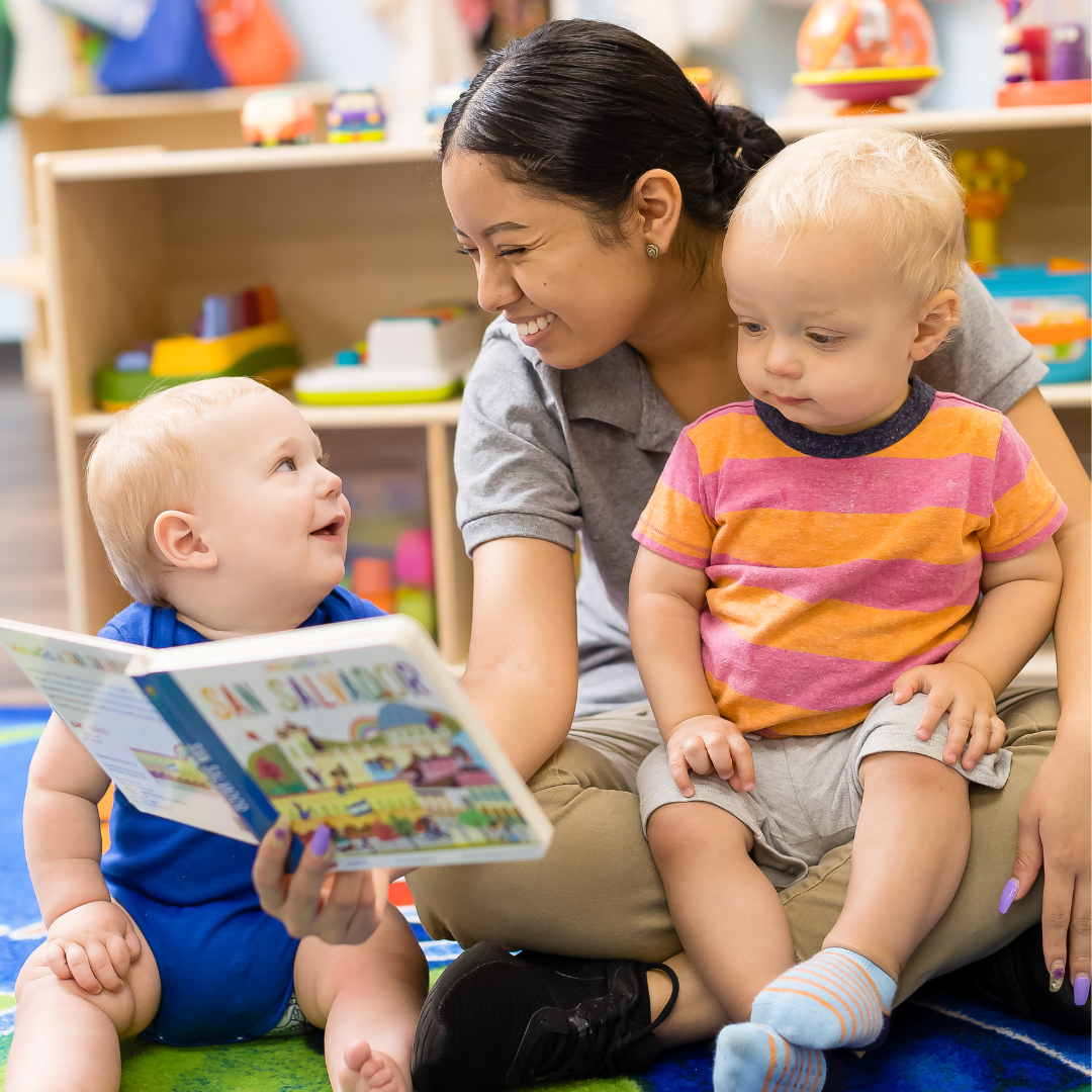 Person reading a book to two children in a classroom