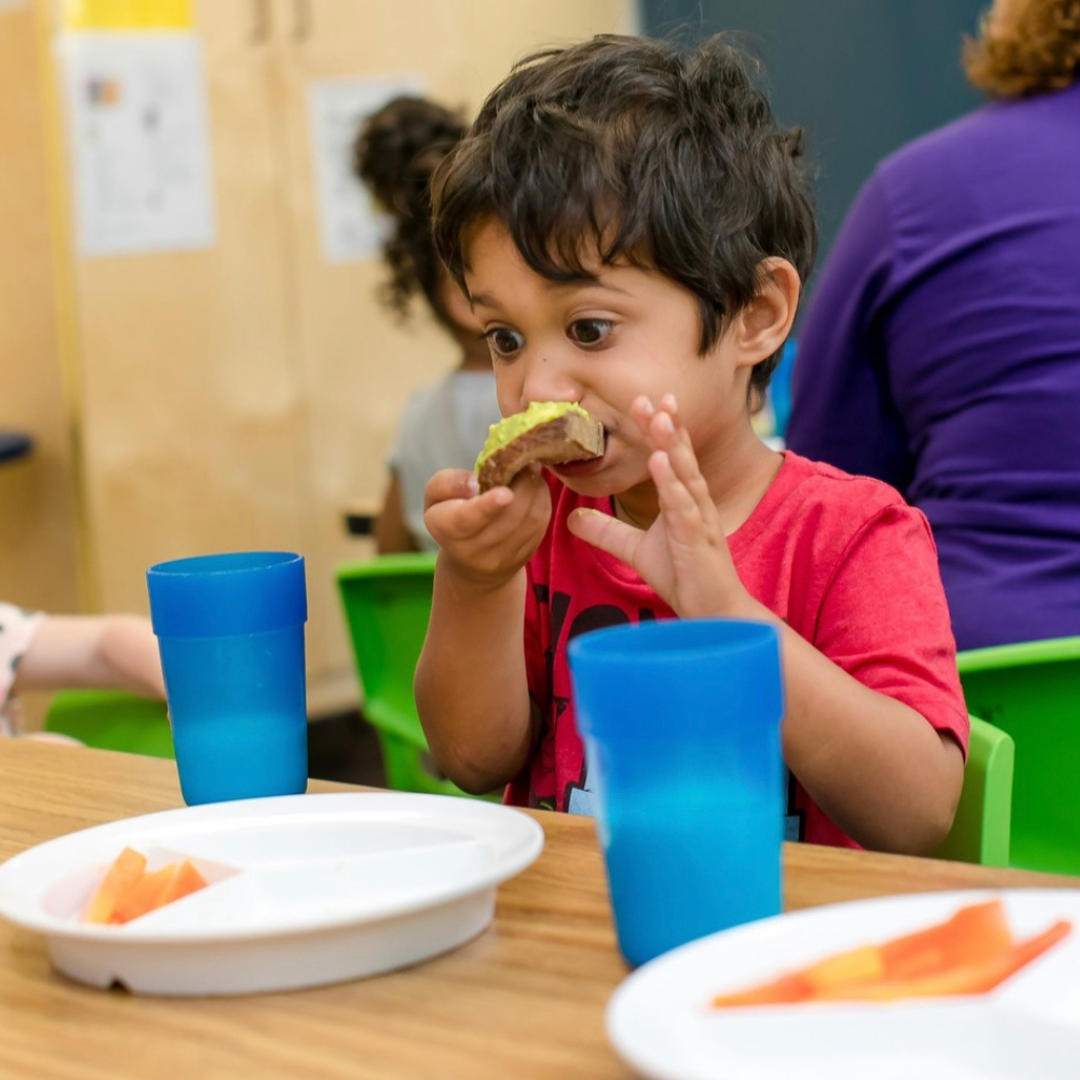 Child eating a piece of food at a table