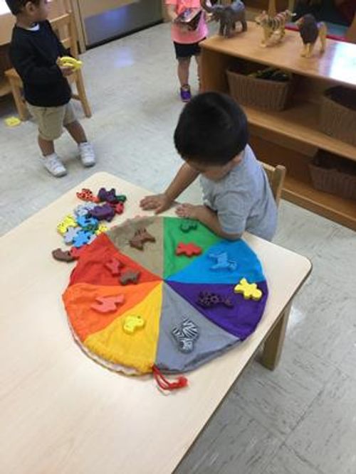 Child playing with a colorful sorting toy on a table