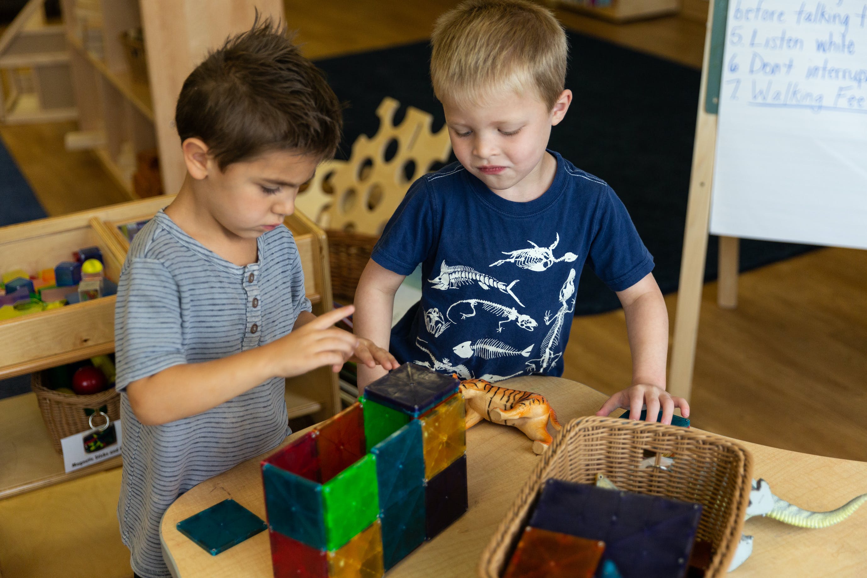 Two children playing with magnetic blocks at a table