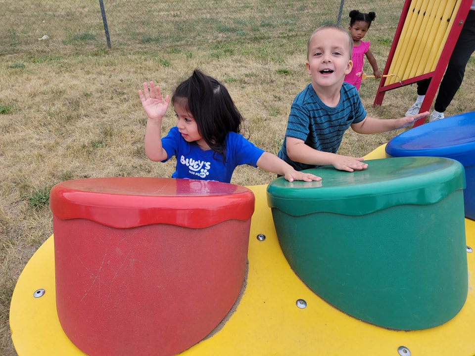 Two children playing on colorful playground equipment
