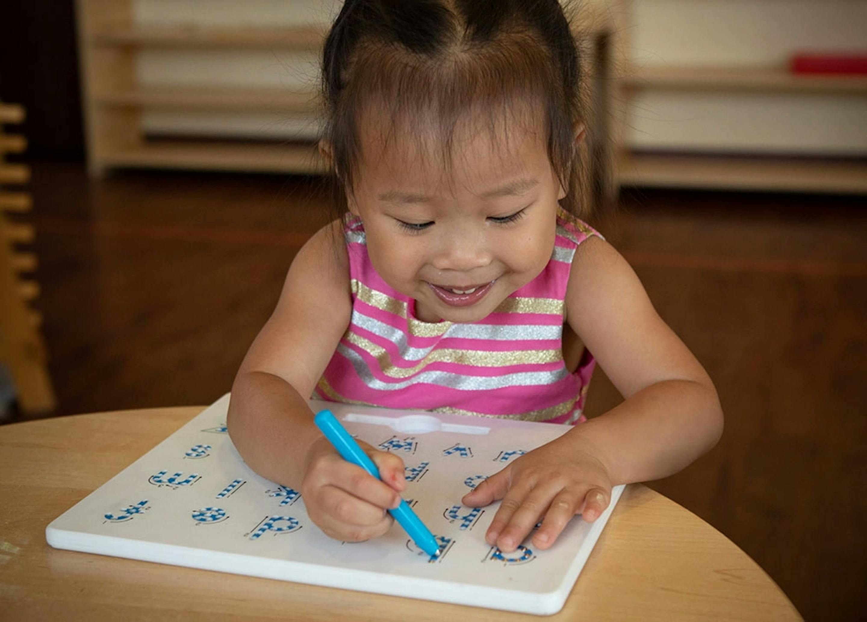 Child drawing on a white board with a blue marker