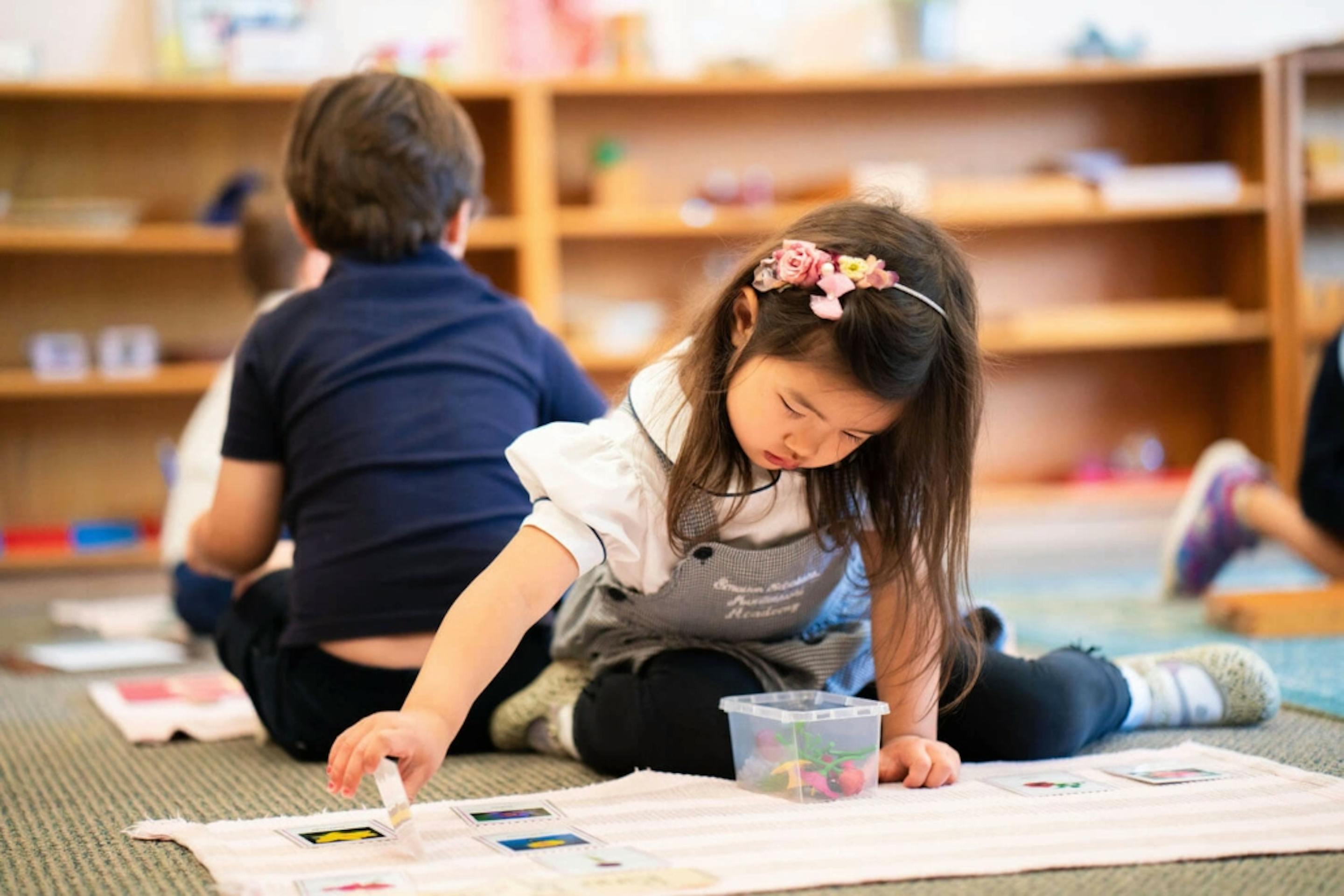 Child sitting on floor working with small objects on a mat