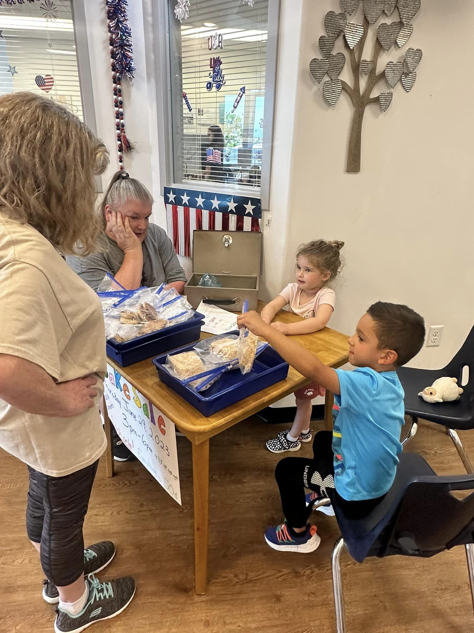 People and children at a table with packaged food items