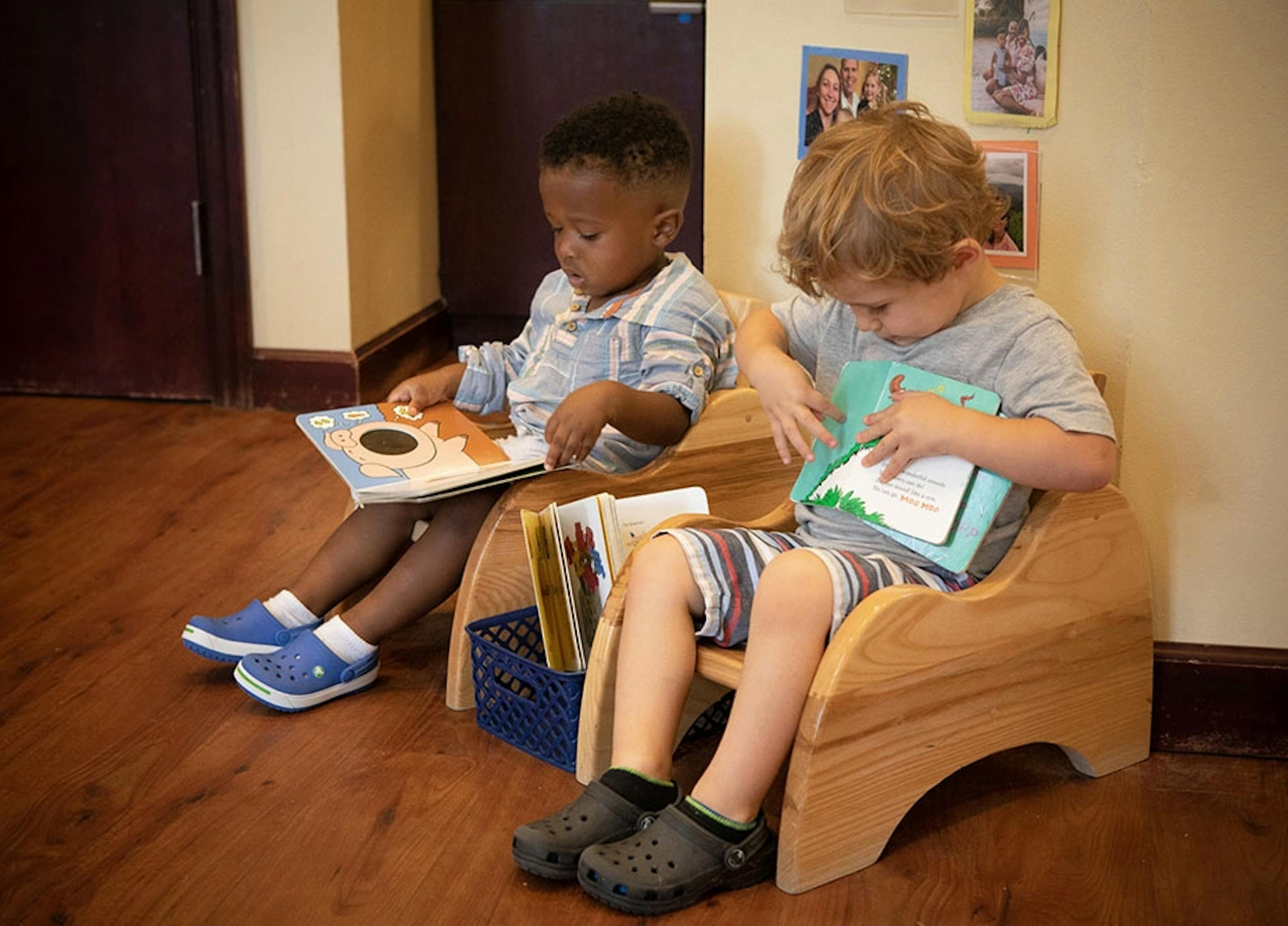 Two children sitting in chairs and reading books
