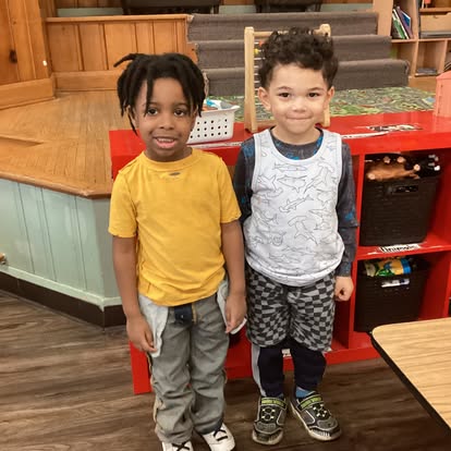 Two children standing next to each other in a classroom