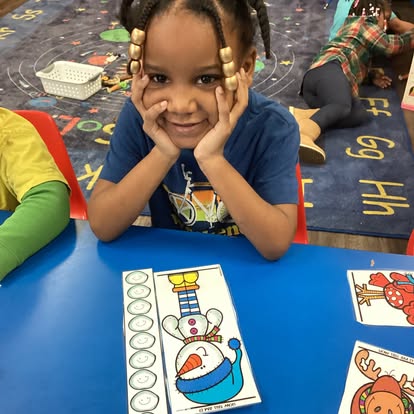 Child with hands on face at a table with snowman puzzle pieces