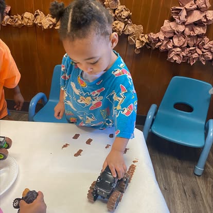 Child playing with a toy truck on a table