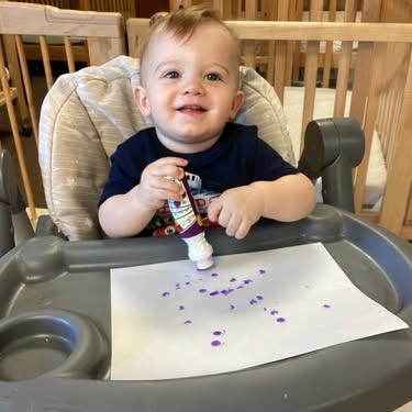 Child in high chair painting on paper