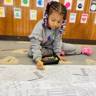 Child coloring on a large paper with crayons