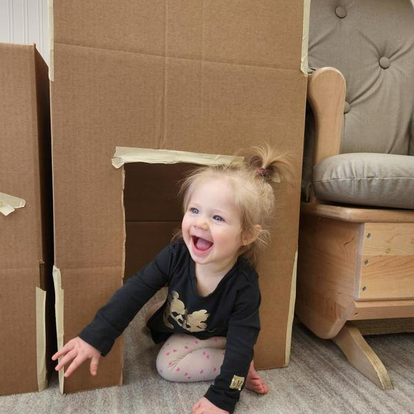 Child playing in a cardboard box fort