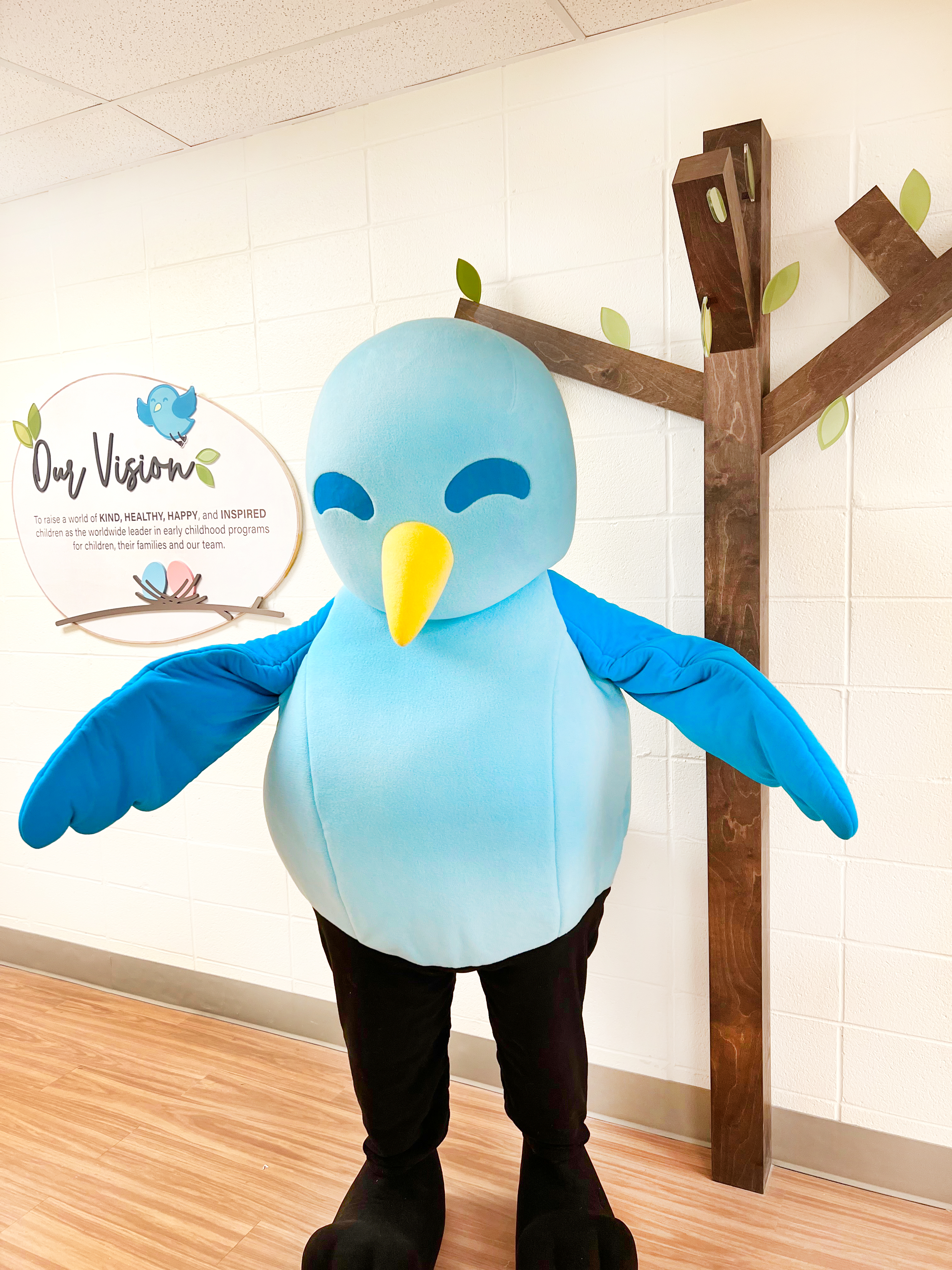 Person in a blue bird mascot costume standing indoors