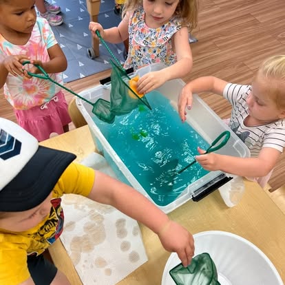 Children using nets to play with objects in a bin of blue water
