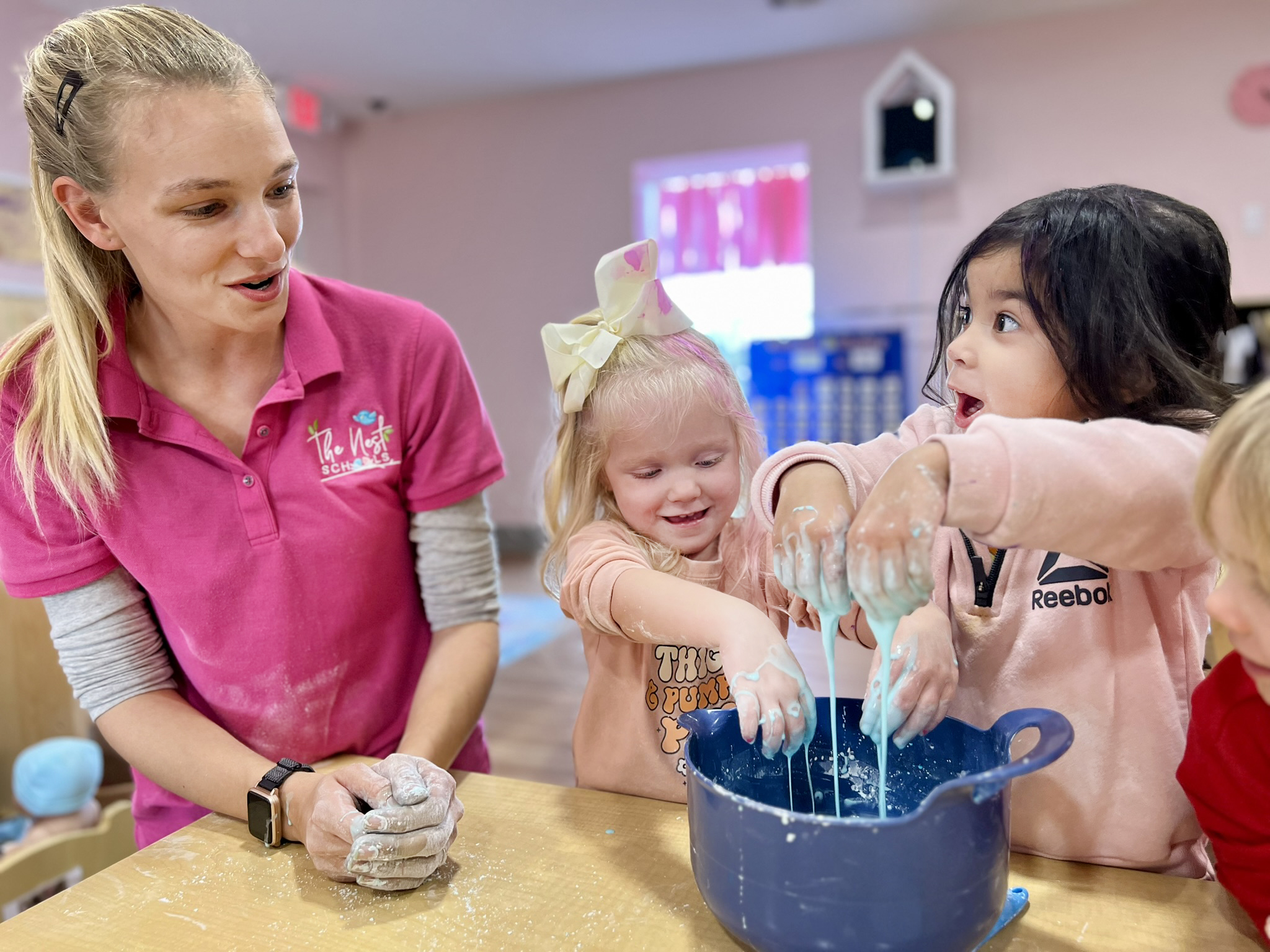 Person and two children playing with slime in a blue bowl