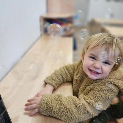 Child in a fuzzy jacket looking at bubbles