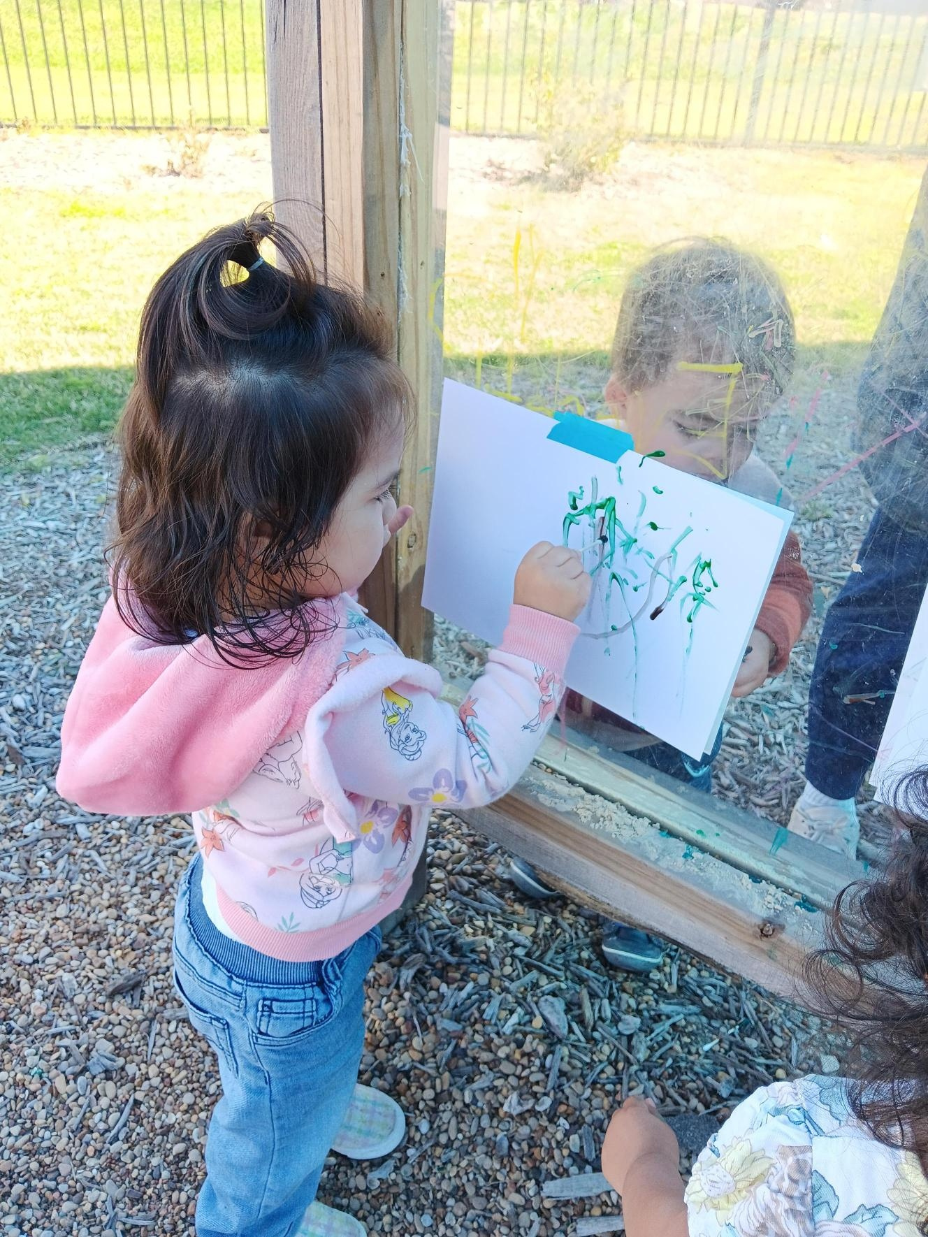 Child drawing on paper taped to a window