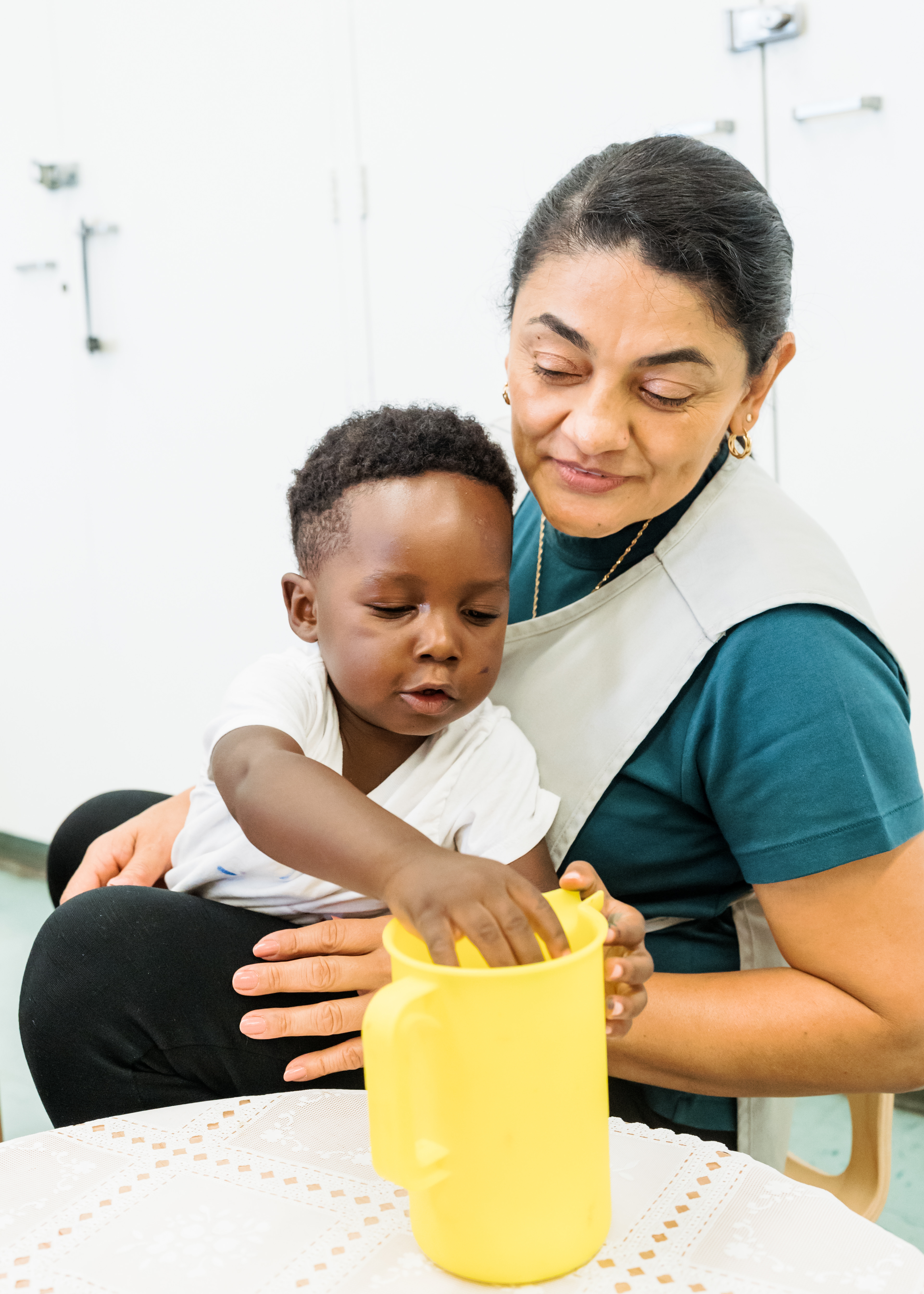 Person holding a child who is reaching into a yellow pitcher