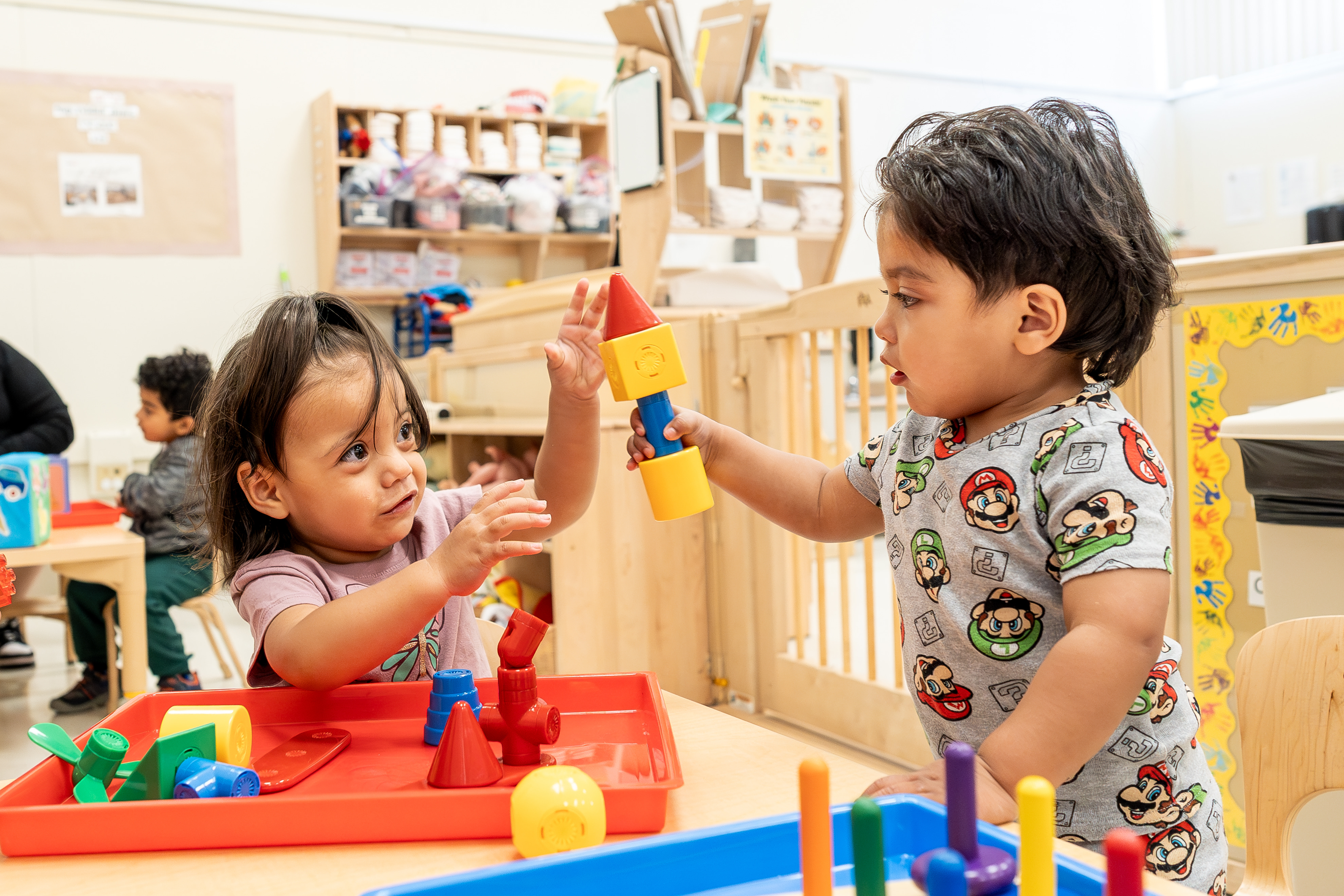 Two children playing with colorful building blocks in a classroom