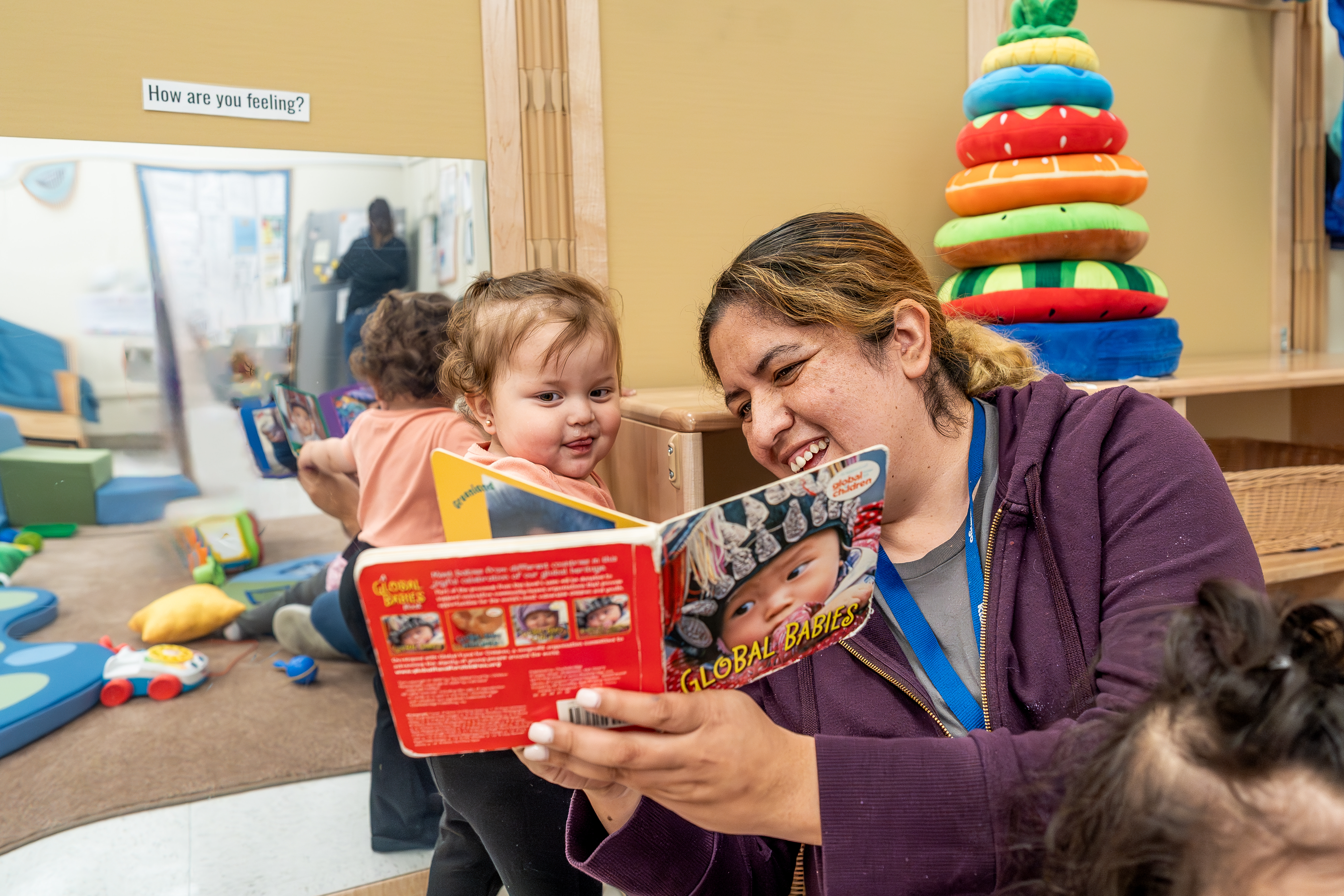 Adult reading a book to two children in a classroom