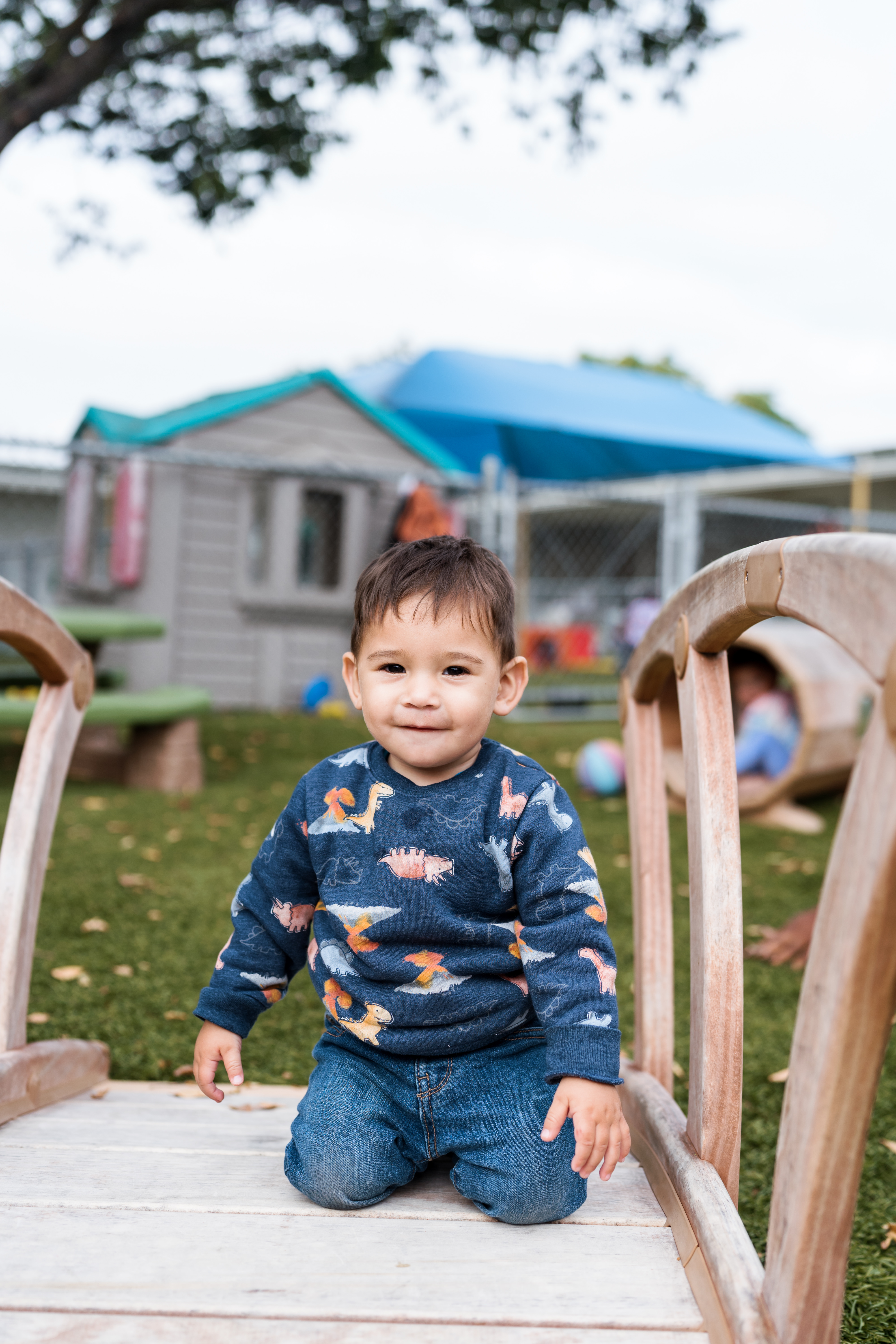 Child kneeling on a small wooden bridge outdoors