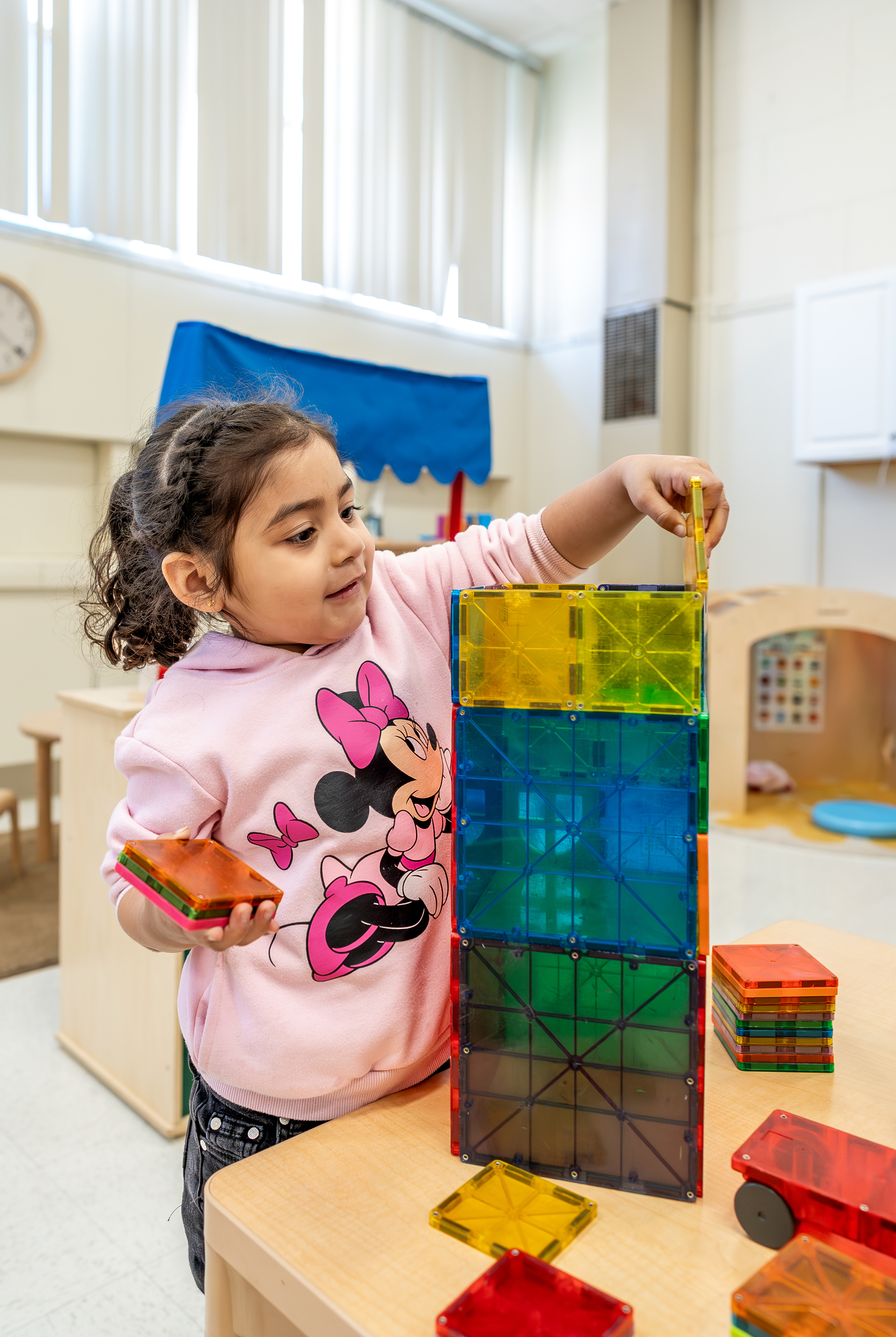 Child building a tower with colorful magnetic blocks in a classroom