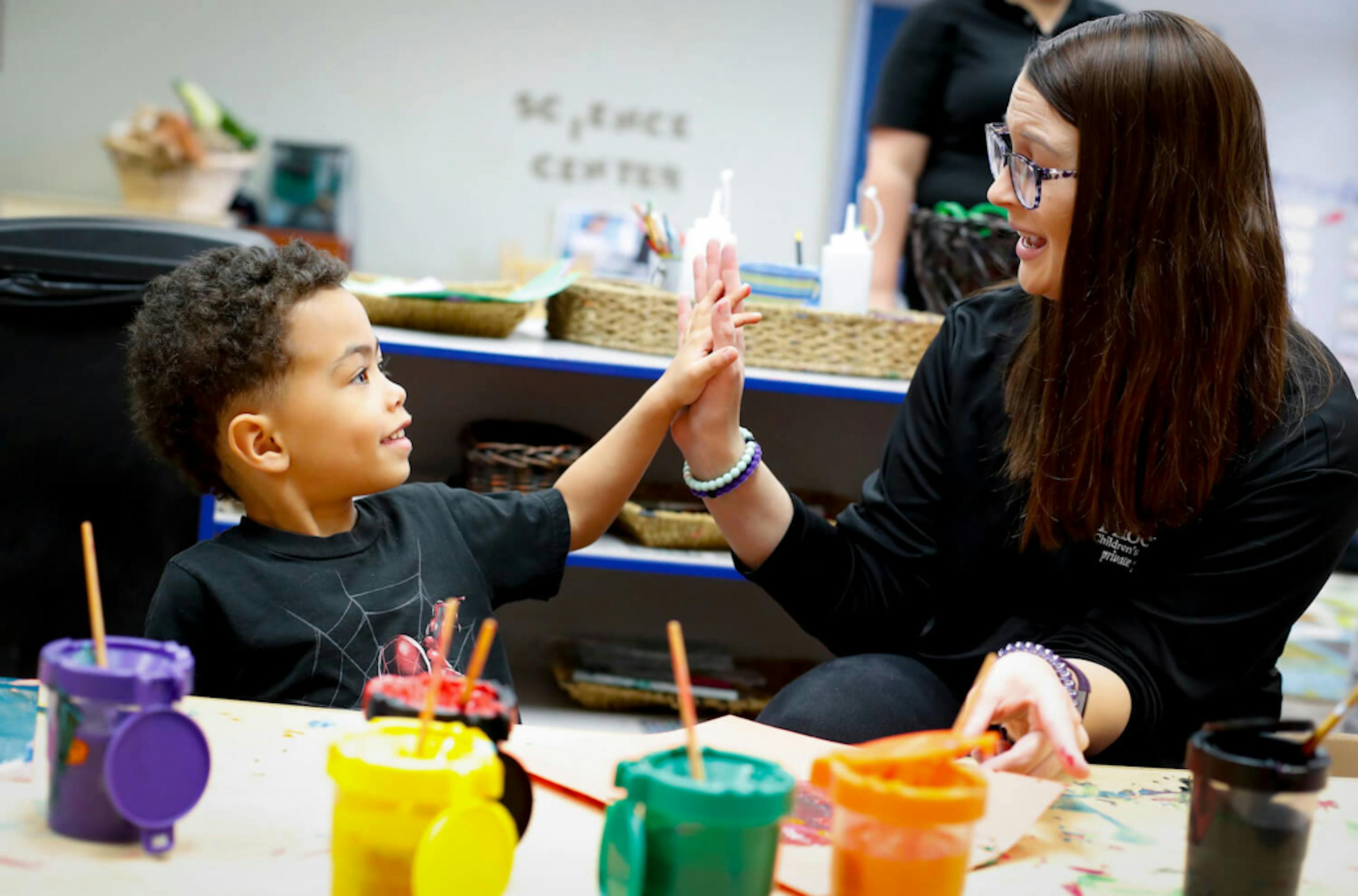 Adult and child high-fiving at a table with colorful cups