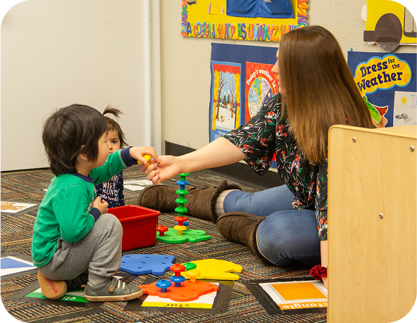 Person and child playing with colorful toys on the floor