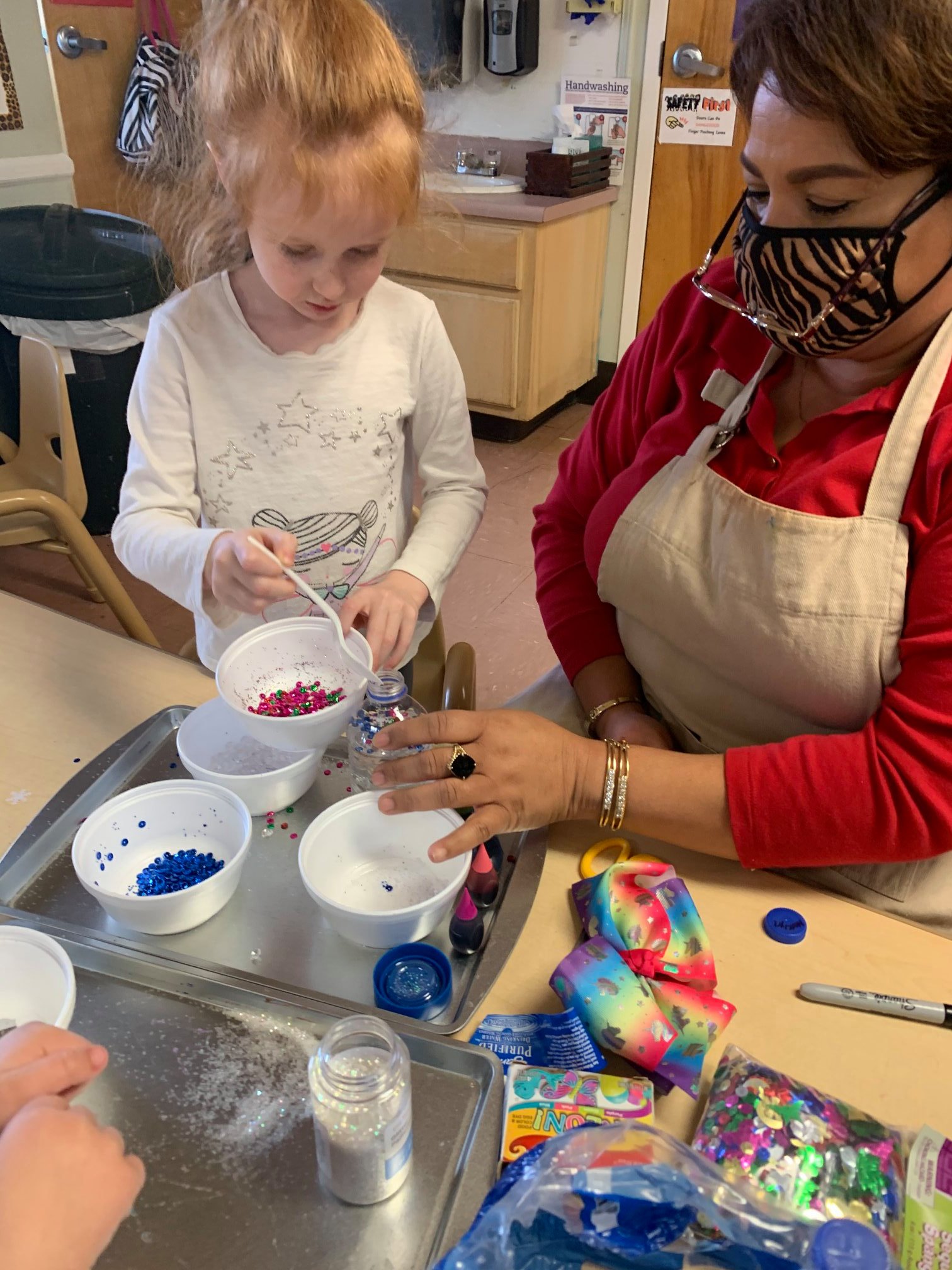 Child and person with mask pouring sprinkles from small bowls