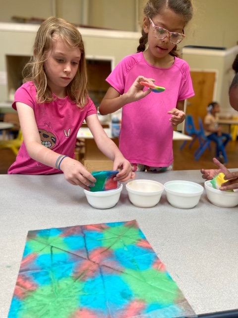 Two children doing a craft with colorful paper and bowls